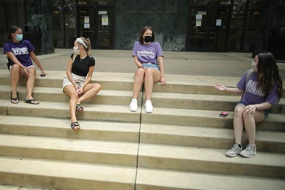 四名足球外围买球靠谱学生的照片，戴着面具，坐在图书馆的台阶上