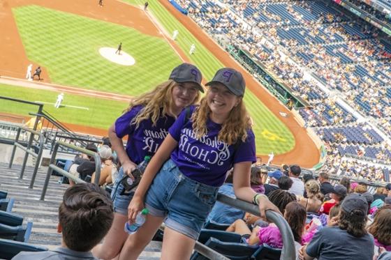  两名足球外围买球靠谱唱诗班的女学生穿着相配的紫色t恤，在匹兹堡海盗队的比赛中合影.
